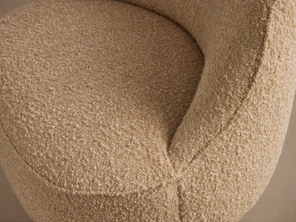 Sonny Swivel Chair, upholstered in textured light beige fabric, with a round base and curved back, on a wooden floor.