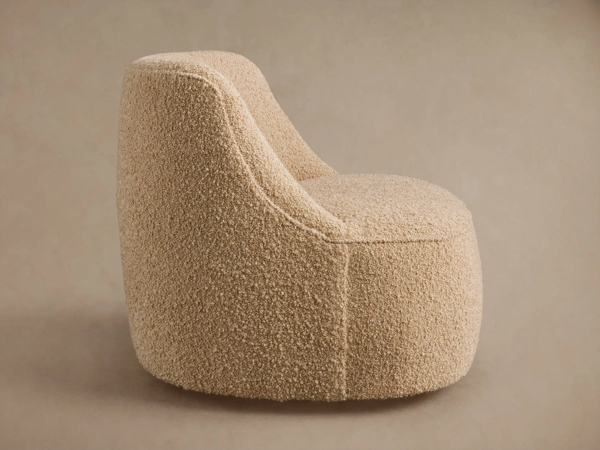 Back view of Sonny Swivel Chair in textured light beige fabric. Rounded, seamless design on a neutral background.