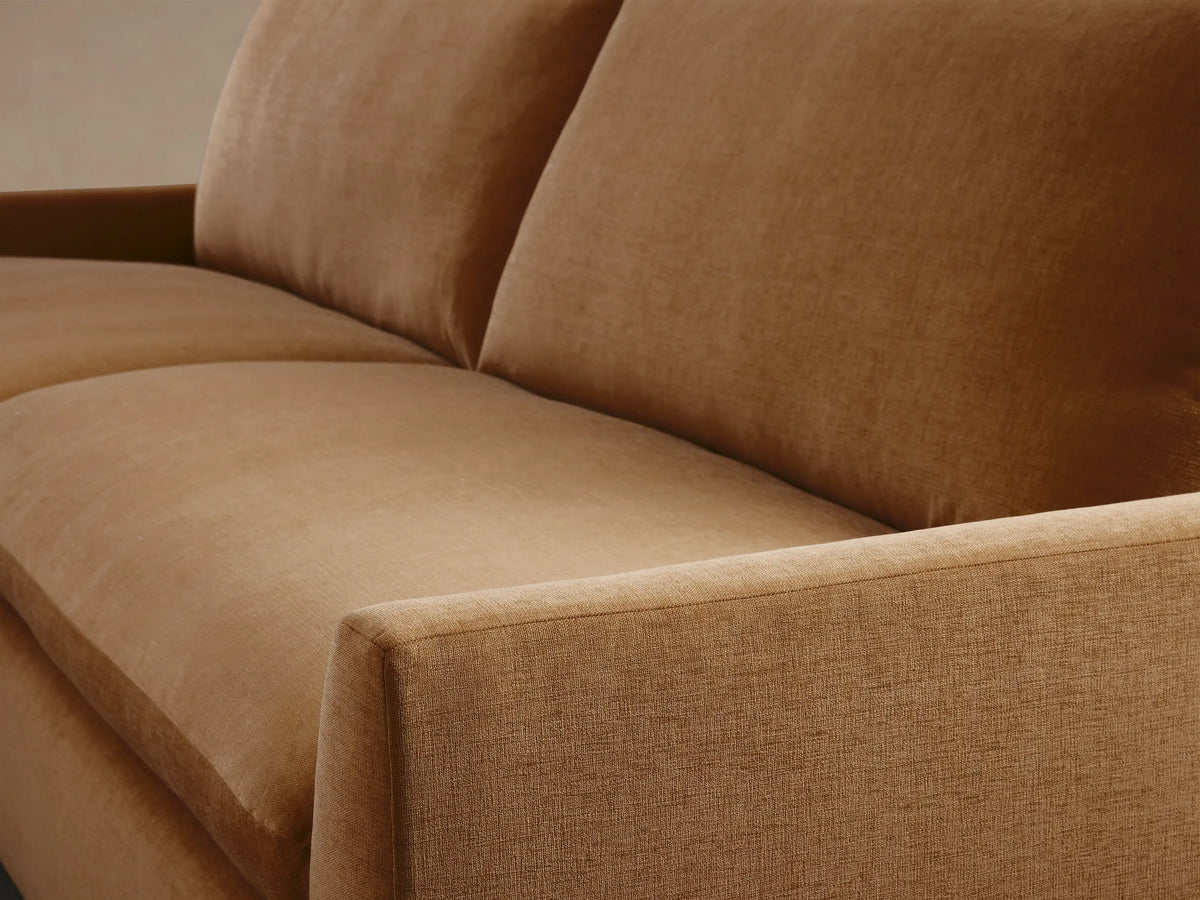 Calistoga Sofa in soft brown fabric, featuring plush cushions and relaxed frame on a hardwood floor with a beige wall backdrop.