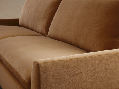 Calistoga Sofa in soft brown fabric, featuring plush cushions and relaxed frame on a hardwood floor with a beige wall backdrop.
