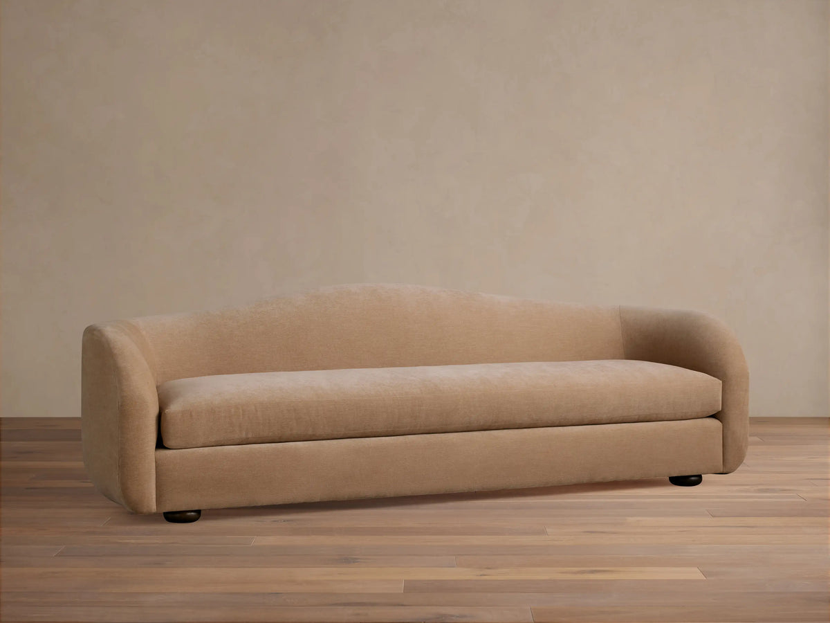 Front view of the cream Ashlyn Sofa, featuring a low profile and curved arms, set in a traditional living room.