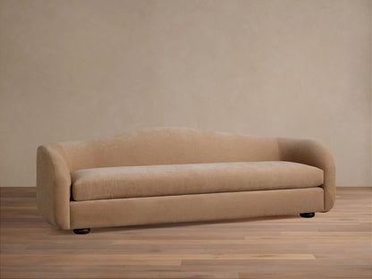 Front view of the cream Ashlyn Sofa, featuring a low profile and curved arms, set in a traditional living room.