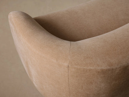 Ashlyn Sofa, a light beige curved sofa with rounded arms, on a wooden floor against a neutral background.