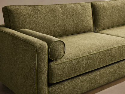 Front view of the Plush Olive Munroe Sofa, featuring two seat and back cushions, bolster pillows, contrast welting, recessed wooden base.