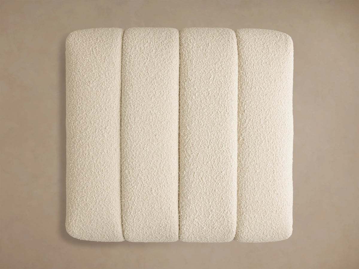 Top-down view of the off-white Bracco Ottoman with four vertical channels and a textured, nubbly fabric finish.