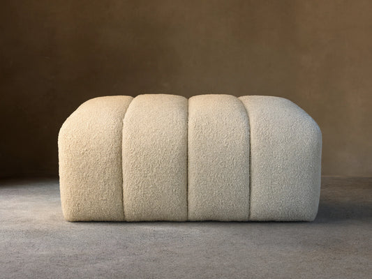 Front view of a cream channel-tufted Bracco Ottoman with rounded edges, upholstered in bouclv© fabric.