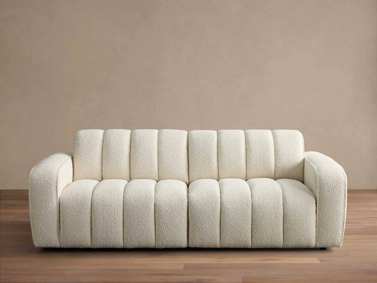 Front view of the cream Bracco Two-Piece Sofa, featuring a soft textured bouclv© fabric and distinctive vertical channel tufting.