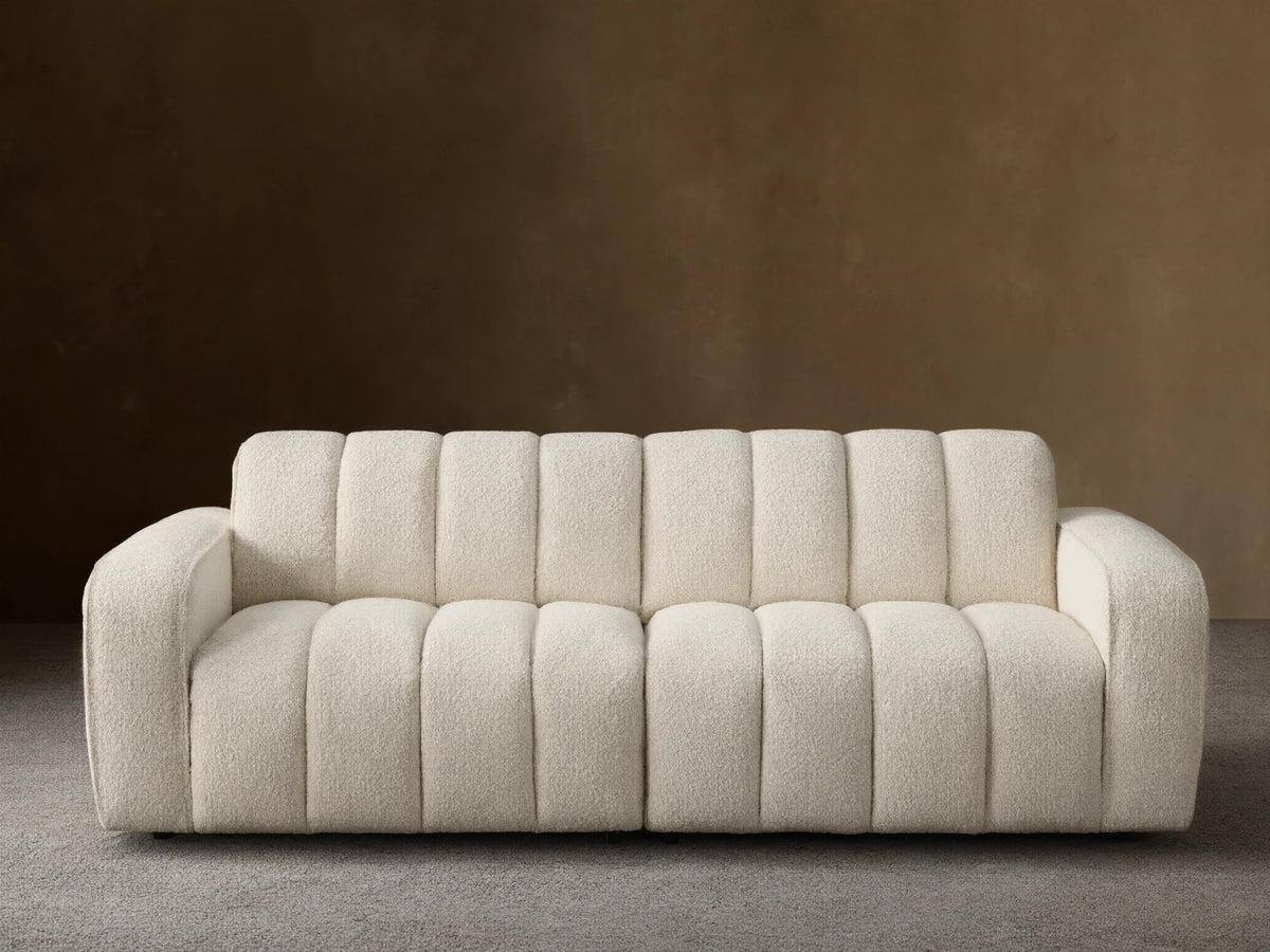 Front view of the cream Bracco Two-Piece Sofa, featuring a soft textured bouclv© fabric and distinctive vertical channel tufting.