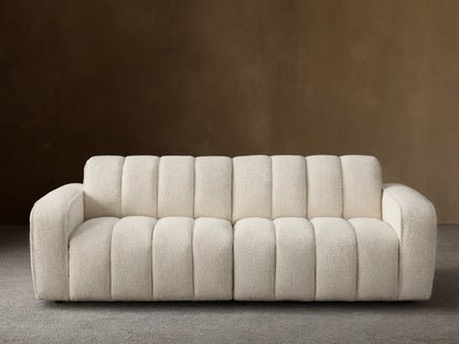 Front view of the cream Bracco Two-Piece Sofa, featuring a soft textured bouclv© fabric and distinctive vertical channel tufting.