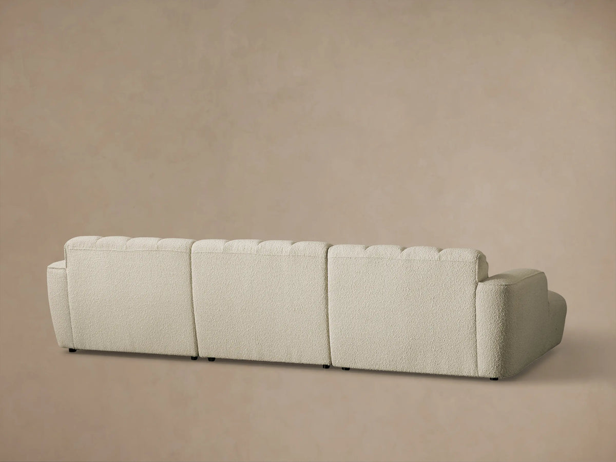 Close-up of the light beige textured fabric on the Bracco Three-Piece Chaise Sectional, highlighting the channel tufting.
