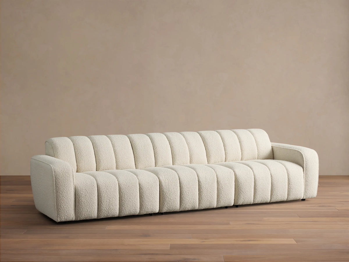 Front view of the cream Bracco Three-Piece Modular Sofa, featuring a textured bouclv© fabric and distinct vertical channeling.