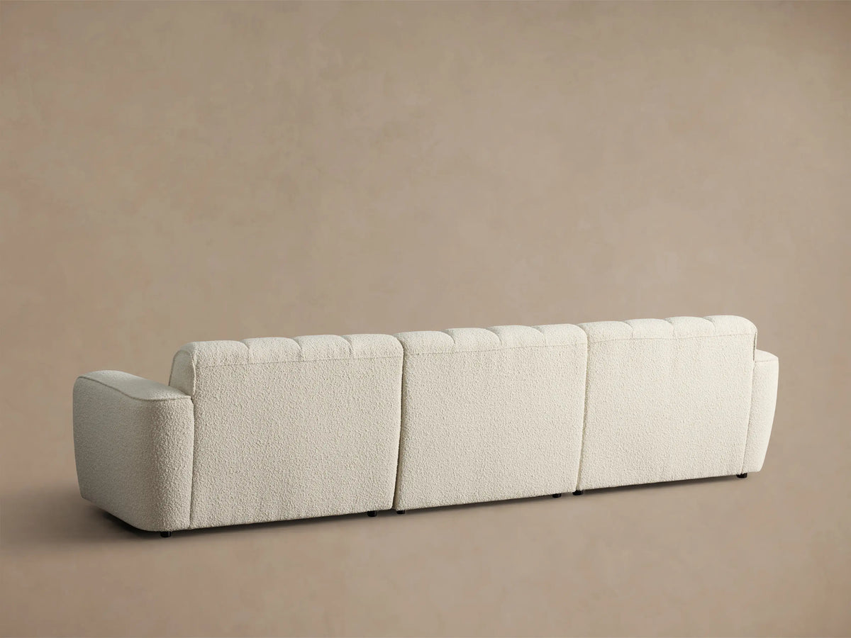 Close-up of a cream Bracco Three-Piece Modular Sofa, showing the bouclv© texture, vertical channel tufting, and rounded armrest.