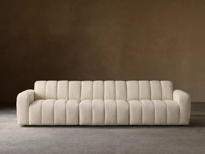 Front view of the cream Bracco Three-Piece Modular Sofa, featuring a textured bouclv© fabric and distinct vertical channeling.