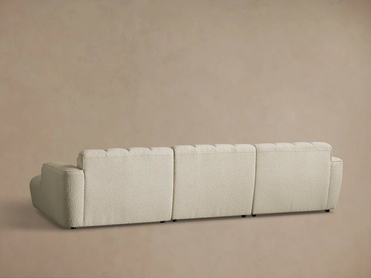 Rear view of the cream textured Bracco Three-Piece Chaise Sectional with segmented, tufted back cushions.