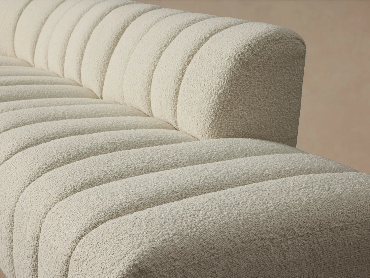 Close-up of the cream bouclé-textured Bracco Five-Piece Bumper Sectional, featuring prominent channel tufting on the seat and backrest.