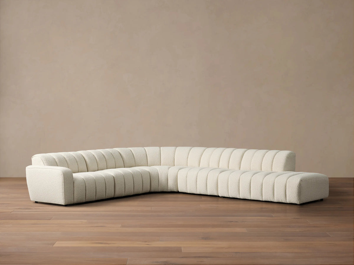 Front view of the cream Bracco Five-Piece Bumper Sectional, featuring channel tufting and a right-side bumper.