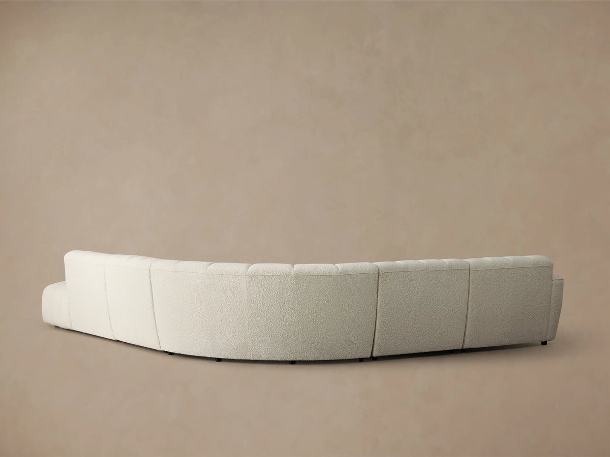 Rear view of the cream Bracco Five-Piece Bumper Sectional, showing its curved shape and textured fabric.