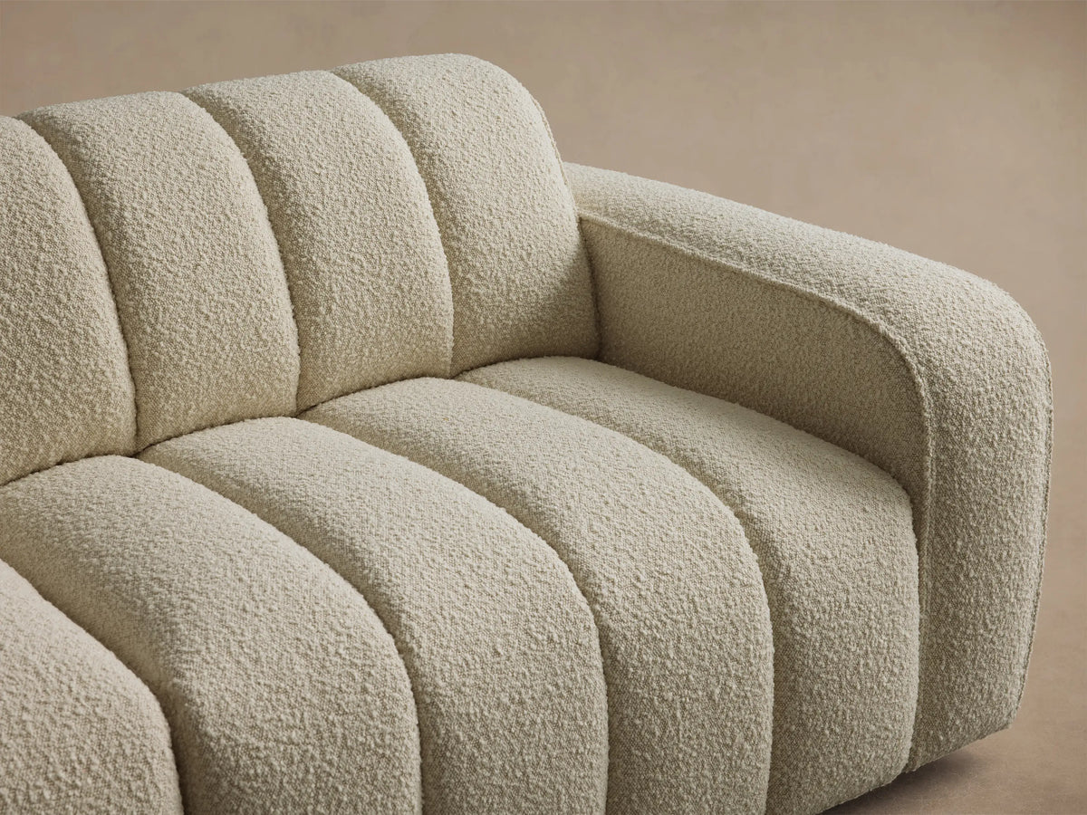 Front view of the cream Bracco Five-Piece Corner Sectional with channeled upholstery on a wooden floor.