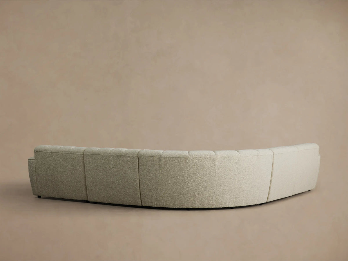 Close-up, angled view of the cream Bracco Five-Piece Corner Sectional, showing vertical channeling and a curved armrest with textured fabric.