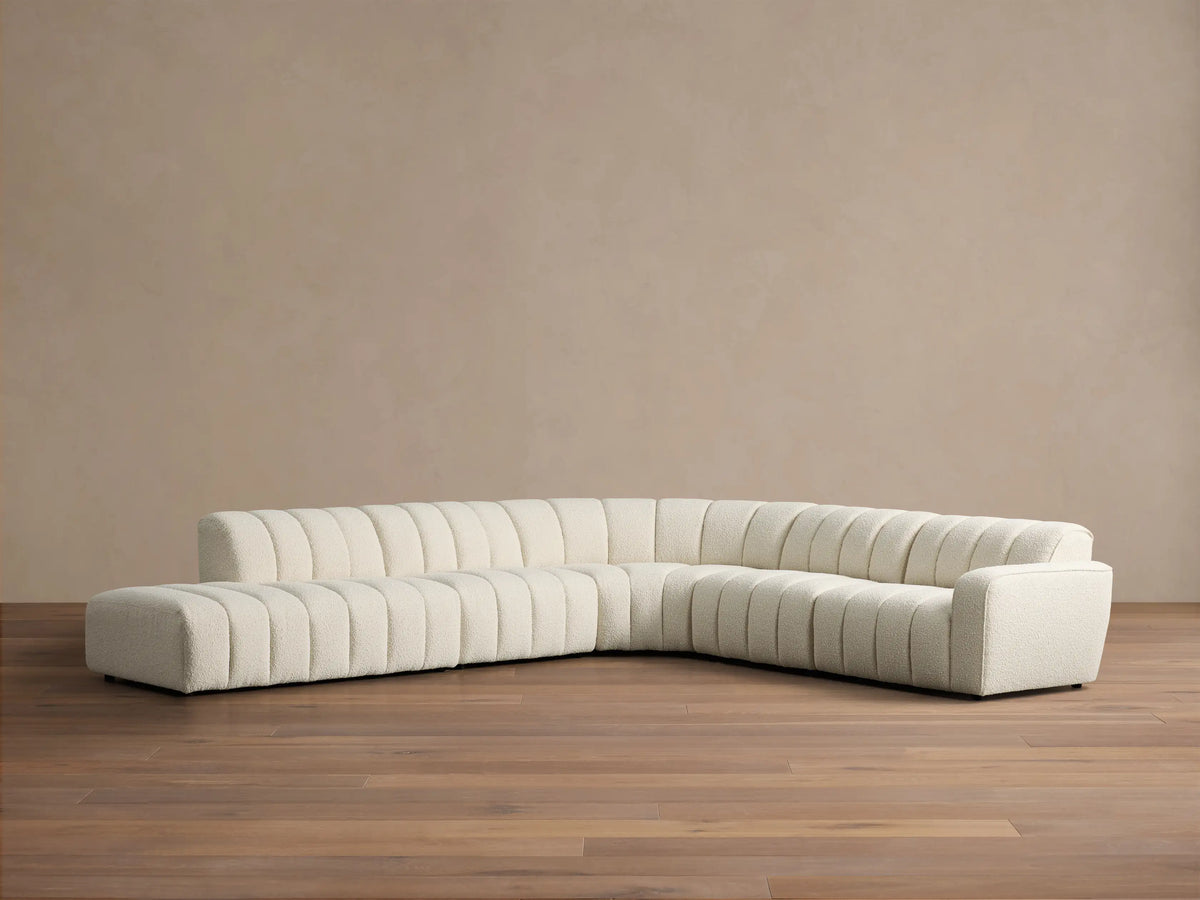 Front view of the cream Bracco Five-Piece Bumper Sectional, L-shaped with vertical channel tufting and boucle fabric.