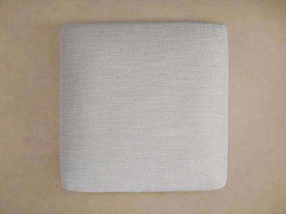 Close-up of a Duncan Ottoman upholstered in light gray fabric, showing the woven texture and a neatly sewn corner.