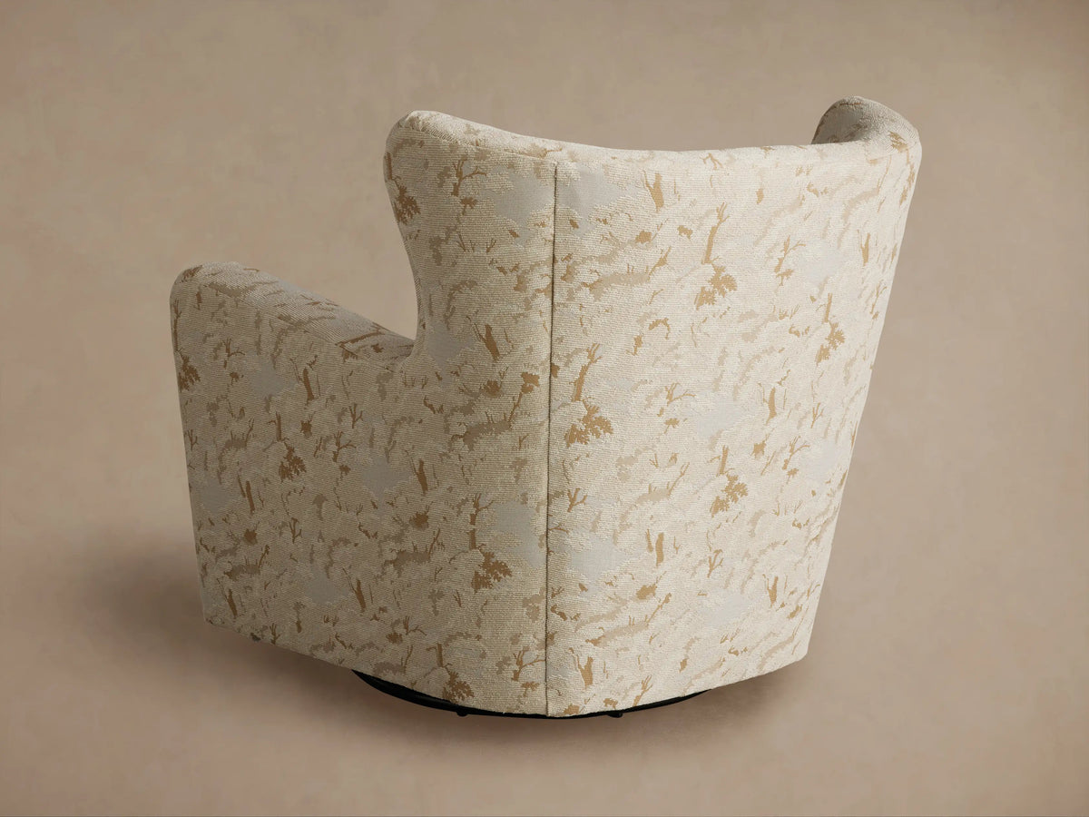 Close-up, angled view of Sasha Swivel Chair's curved arm and back, upholstered in cream textured fabric with tan abstract pattern.