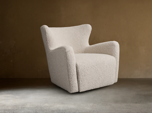 A cream-colored Sasha Swivel Chair with a textured fabric. It features a rounded backrest and armrests, set on a wooden floor.
