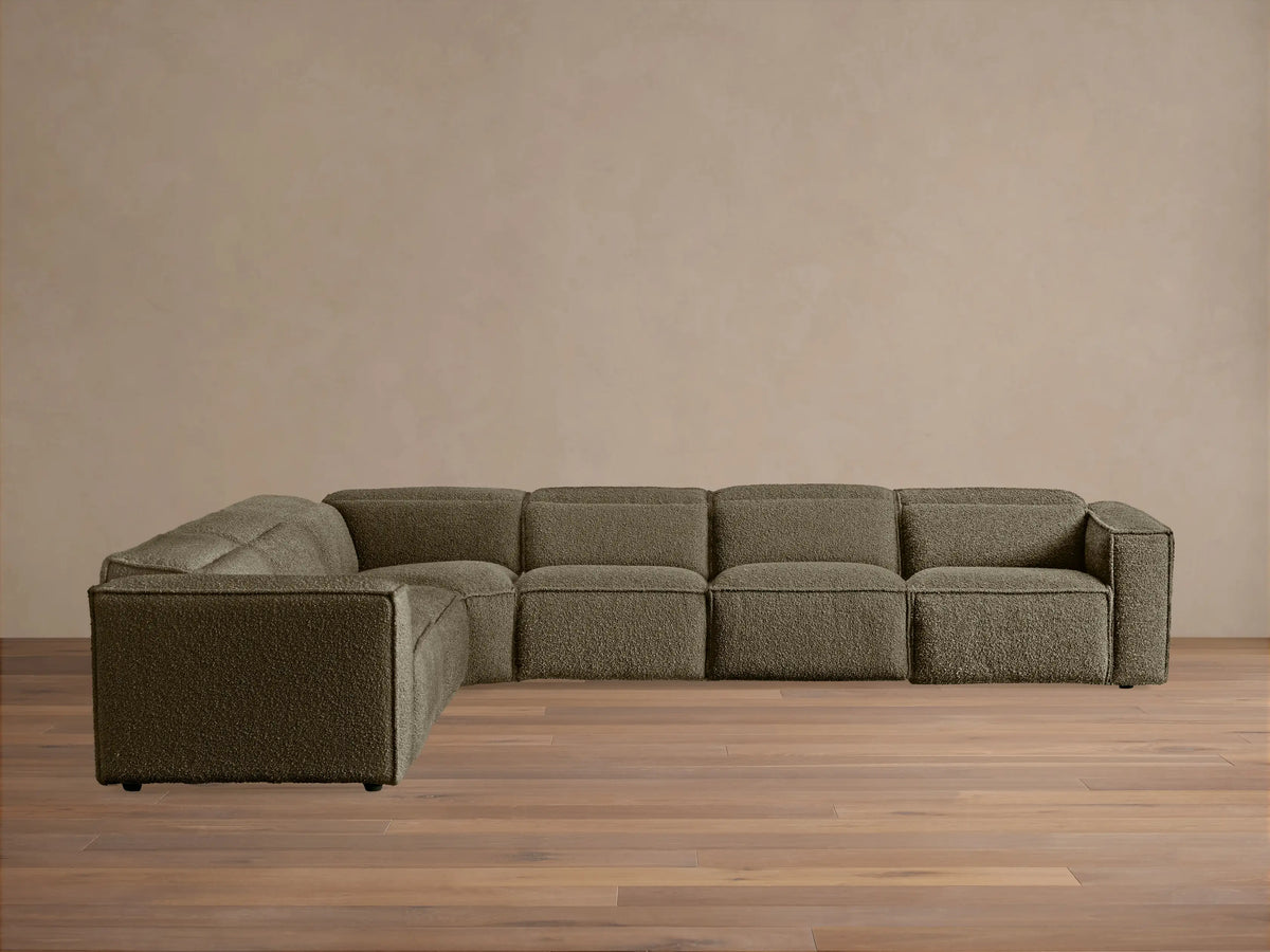 Coburn Six-Piece Motion Sectional, L-shaped, in deep olive textured fabric against a light wall on a wood floor.