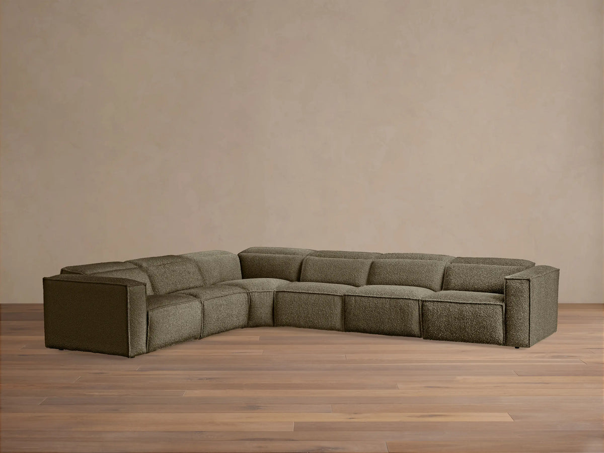 Coburn Six-Piece Motion Sectional, L-shaped, in deep olive textured fabric against a light wall on a wood floor.