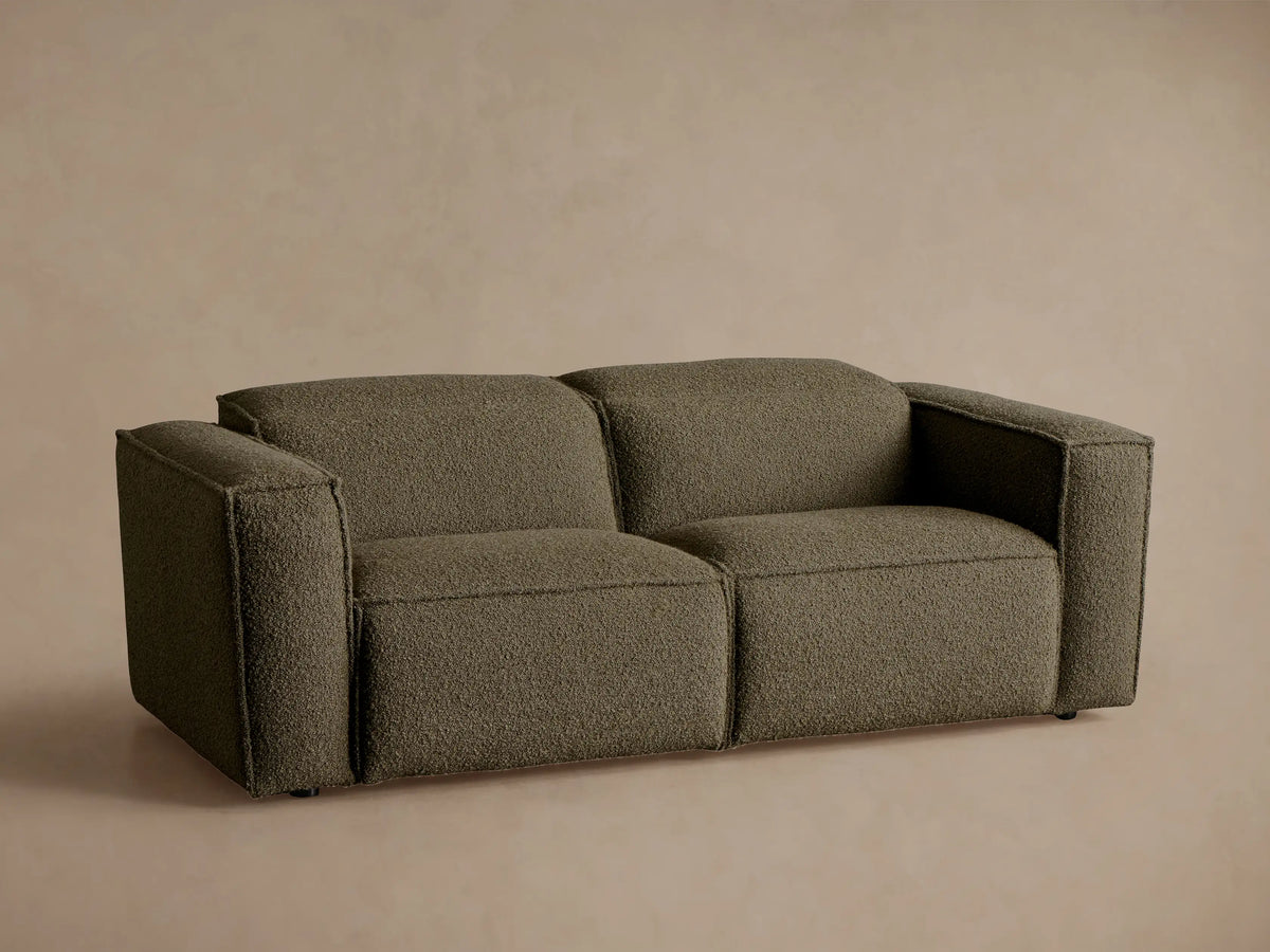 Coburn Two-Piece Motion Sofa in dark olive green textured fabric, a modern two-seater with square arms, on a wood floor.
