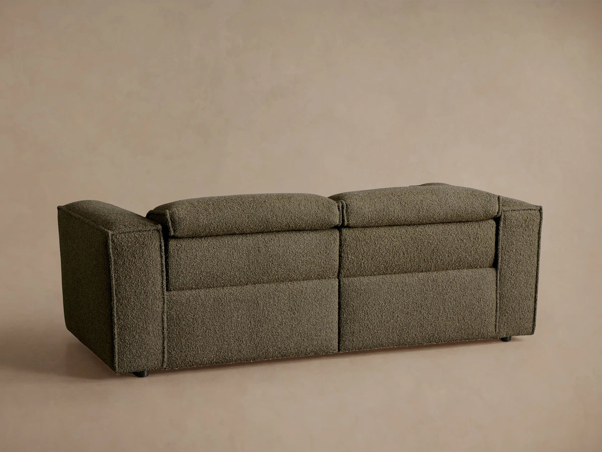 Coburn Two-Piece Motion Sofa close-up: textured olive Crypton fabric with a dark brown oval two-button recliner control.