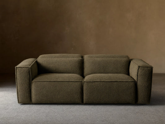 Coburn Two-Piece Motion Sofa in dark olive green textured fabric, a modern two-seater with square arms, on a wood floor.