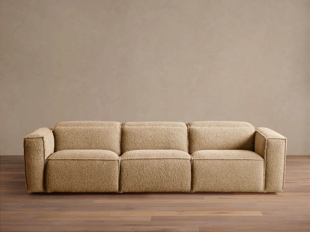 Coburn Three-Piece Motion Sofa in light brown textured fabric, full front view on a wooden floor against a beige wall.