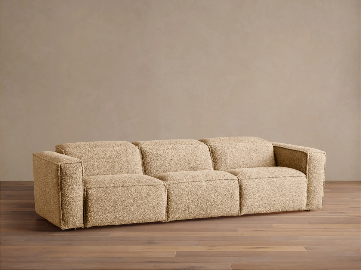 Coburn Three-Piece Motion Sofa in light brown textured fabric, full front view on a wooden floor against a beige wall.