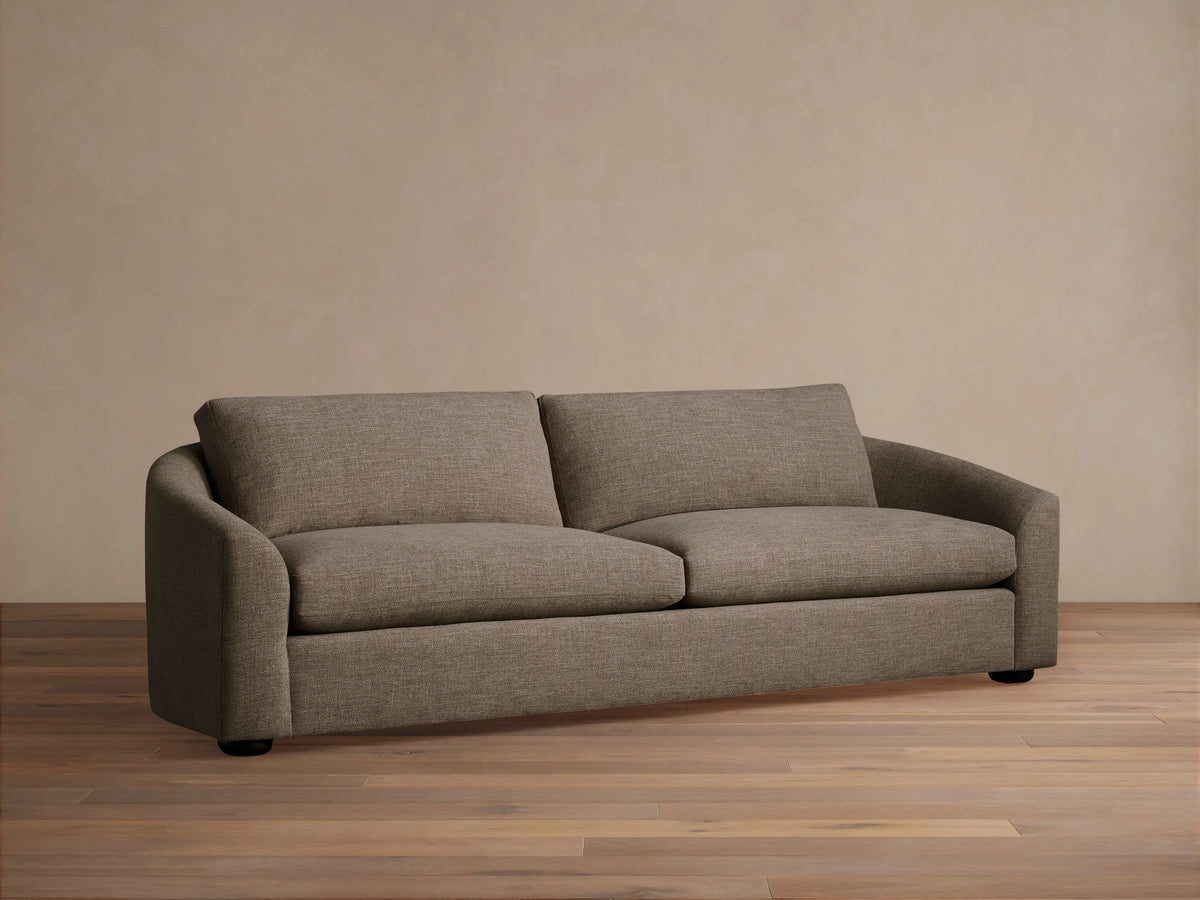 Front view of a light cream Avon Sofa with plush cushions and brown and cream accent pillows.
