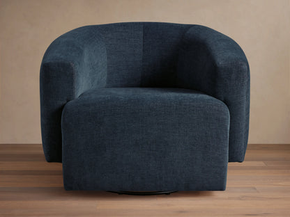 Dark blue Hamlin Swivel Chair on wooden floor, featuring a rounded backrest and armrests. Chair has a solid steel swivel base.