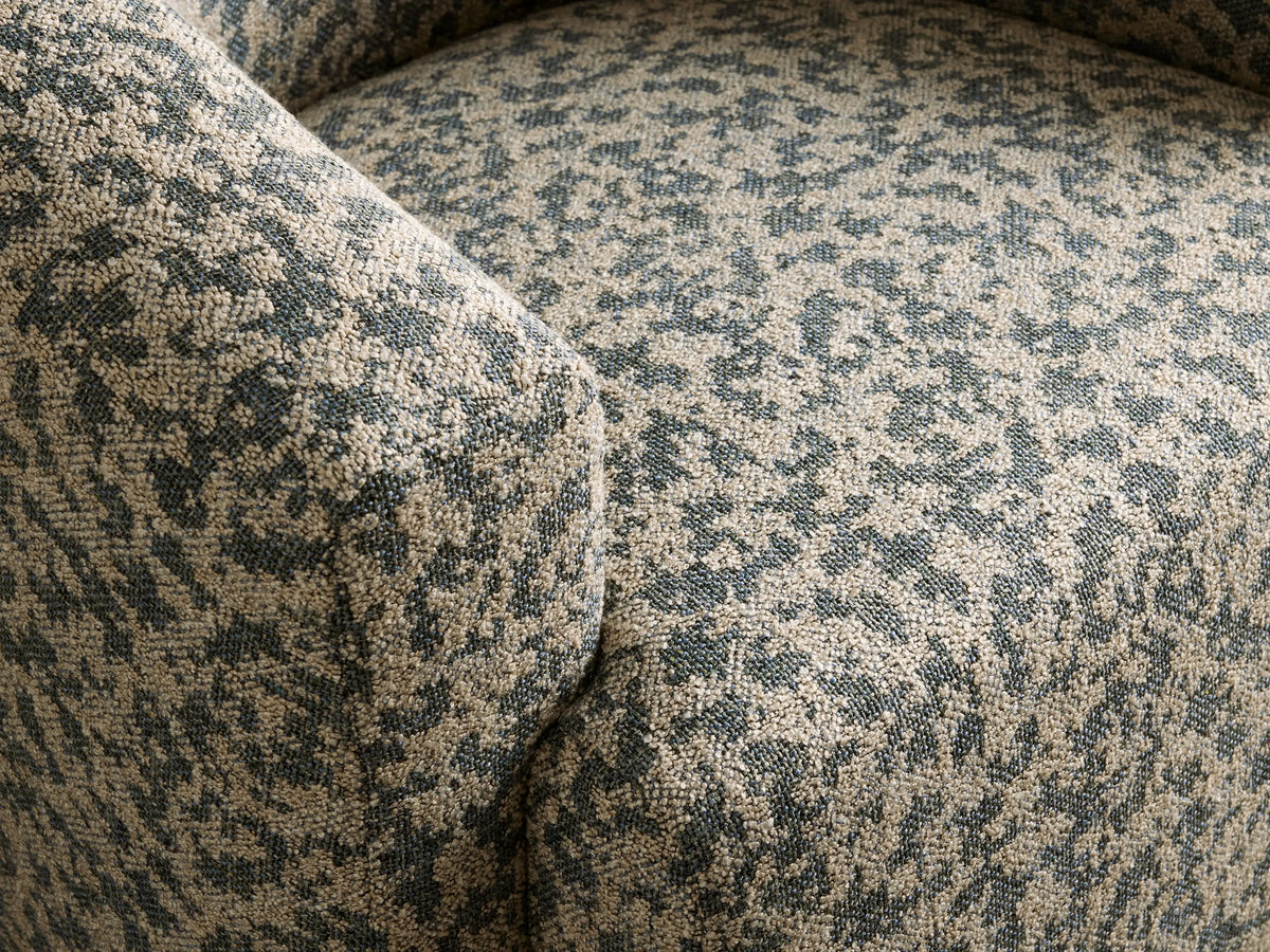 Hamlin Swivel Chair, rounded barrel style, upholstered in mottled dark teal & beige fabric, on a wood floor.