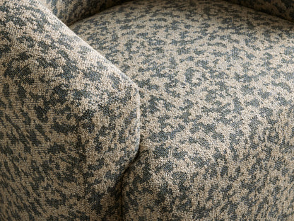 Hamlin Swivel Chair, rounded barrel style, upholstered in mottled dark teal & beige fabric, on a wood floor.