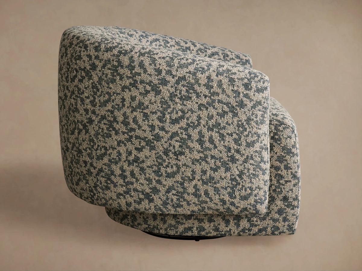 Round Hamlin Swivel Chair in mottled beige & blue-green fabric, seen side-rear with black swivel base.
