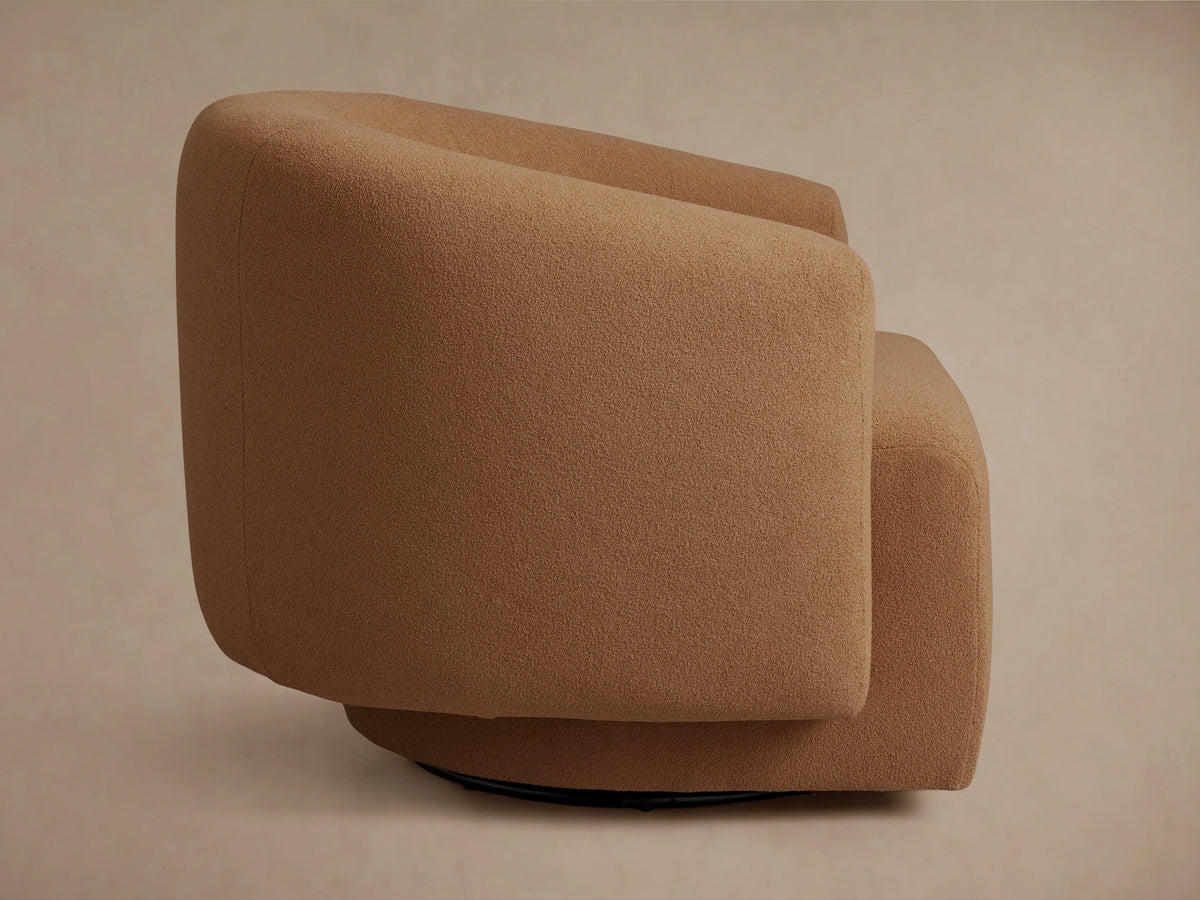 Close-up of richly textured, medium brown fabric with subtle shadows, forming a gentle curve, likely part of a comfortable sofa or chair.