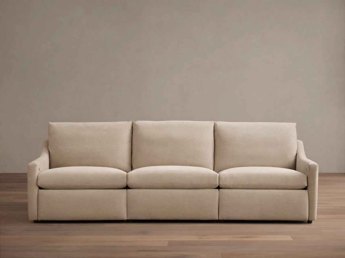 Front view of the beige Kipton Slope Arm Three-Piece Motion Modular Sofa with three cushions and three motion bases.