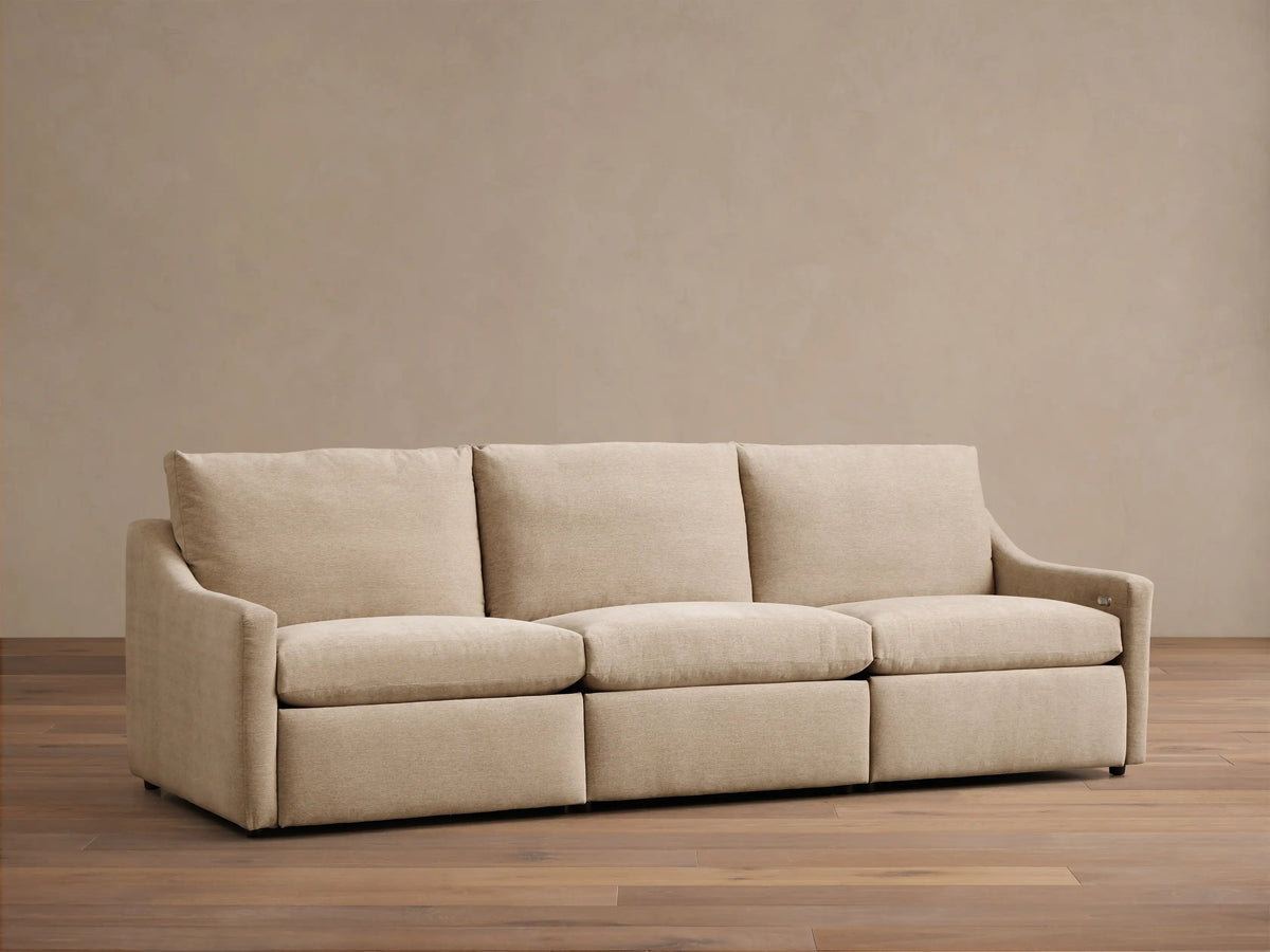 Front view of a light beige Kipton Slope Arm Three-Piece Motion Modular Sofa with three cushions and gentle slope arms.