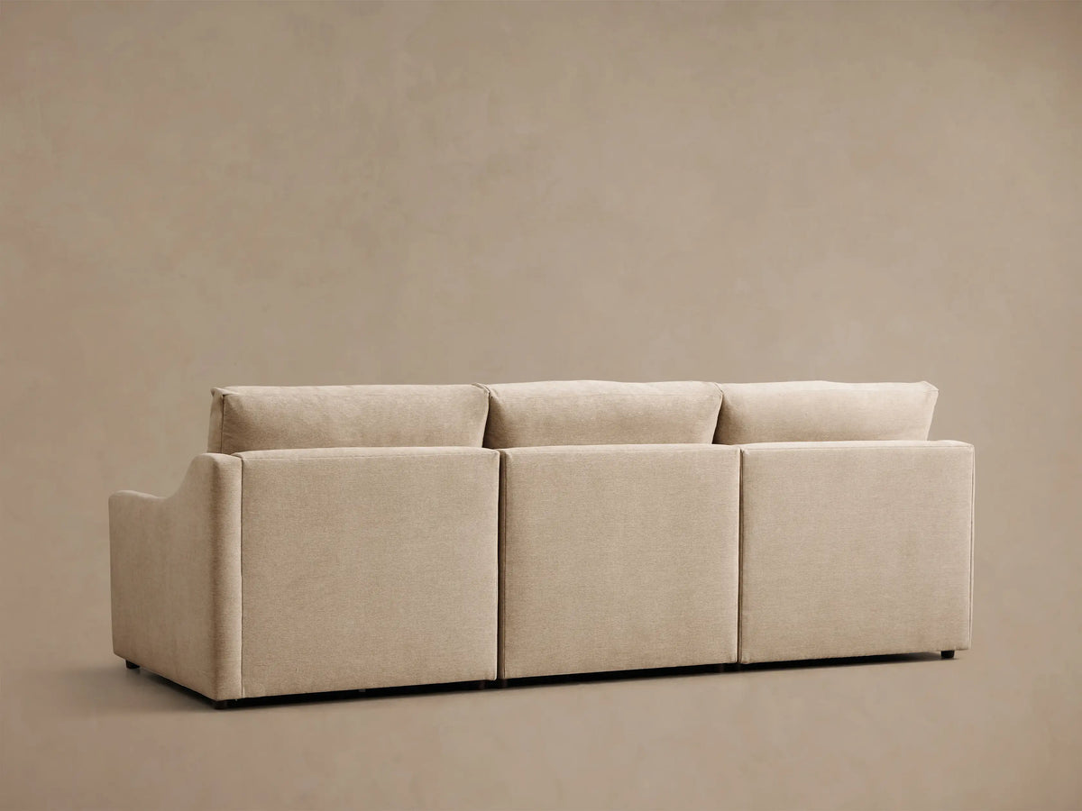 Rear and left side view of a beige Kipton Slope Arm Three-Piece Motion Modular Sofa, featuring three distinct back cushions.
