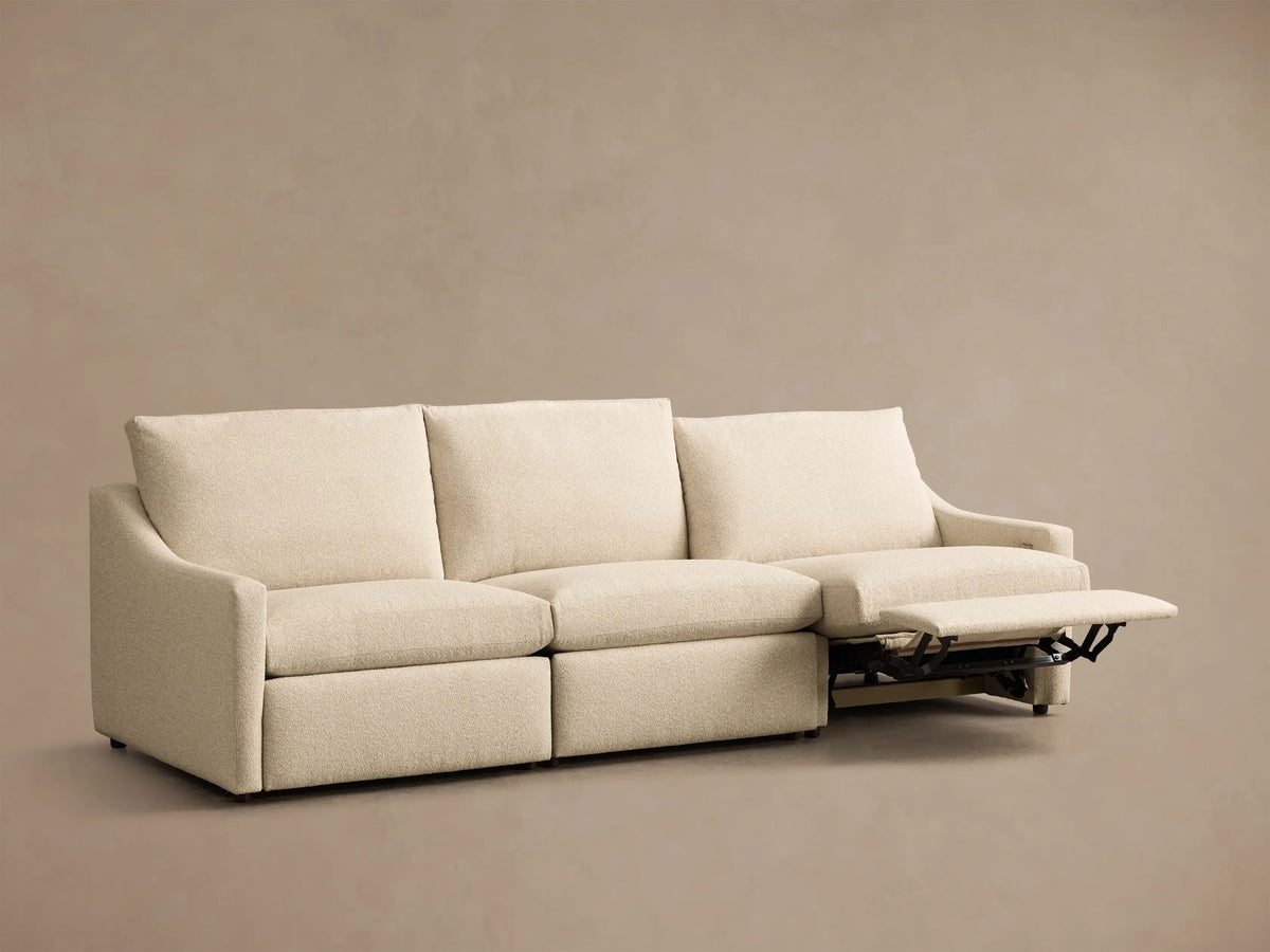 Front view of a cream Kipton Slope Arm Three-Piece Motion Modular Sofa with sloped arms and one footrest extended.