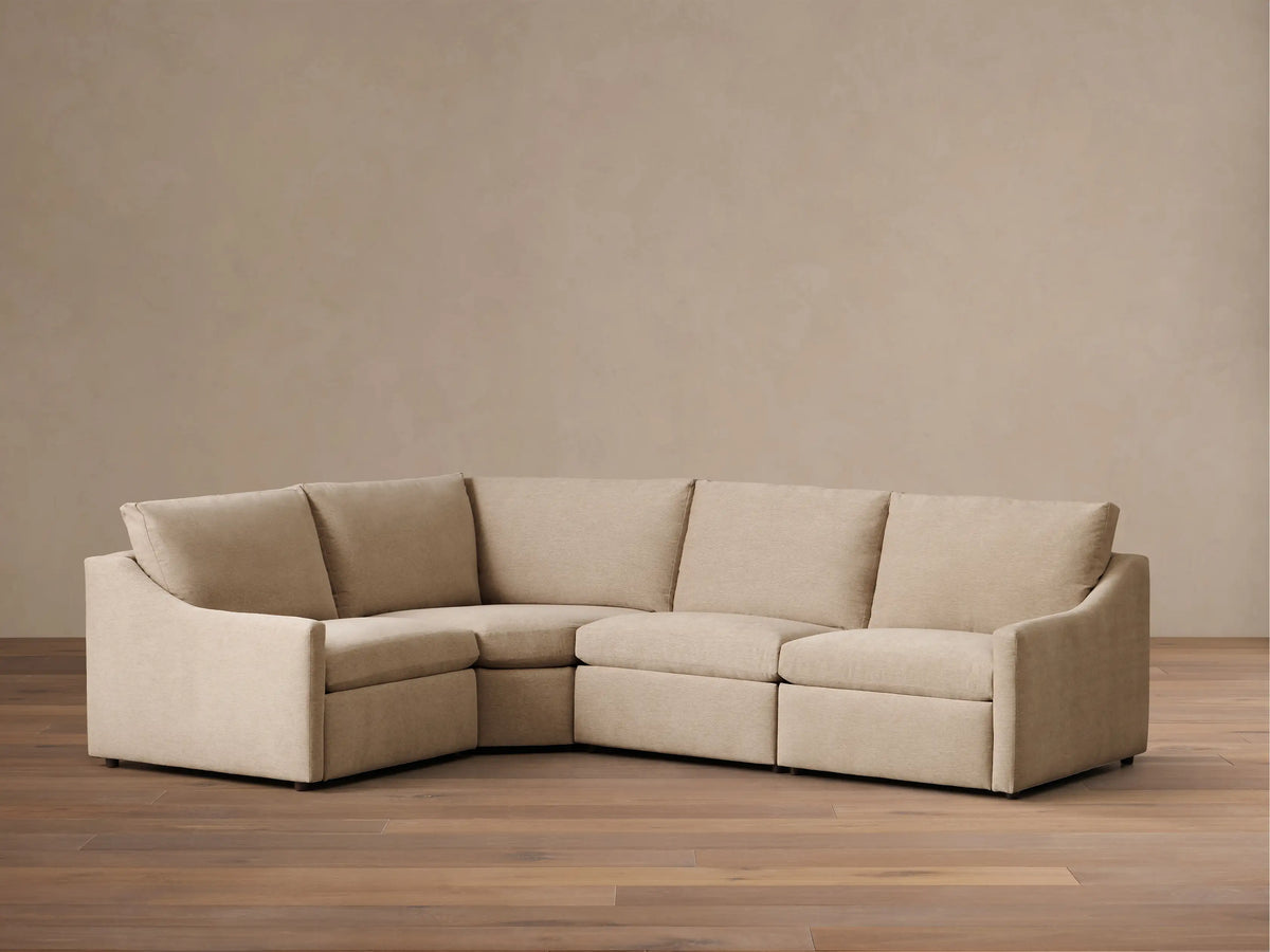 Front view of the beige Kipton Slope Arm Four-Piece Motion Sectional, arranged in an L-shape with a sloped left arm.