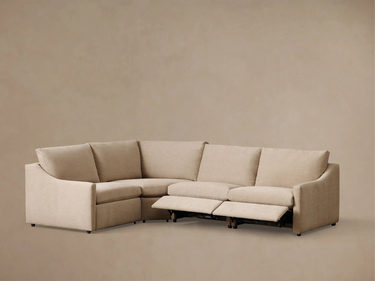 Front view of a light beige Kipton Slope Arm Four-Piece Motion Sectional with one recliner extended.