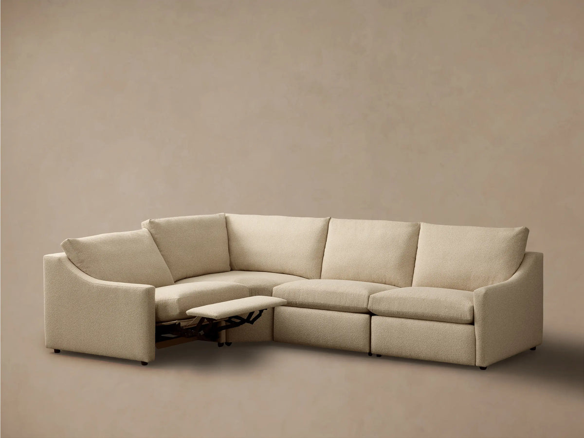 Front view of a light beige Kipton Slope Arm Four-Piece Motion Sectional with one extended footrest.