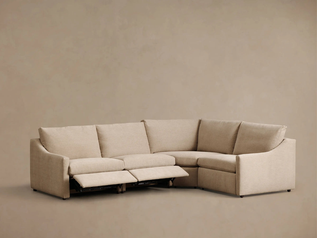 Front view of the light beige Kipton Slope Arm Four-Piece Motion Sectional with one reclining footrest extended.