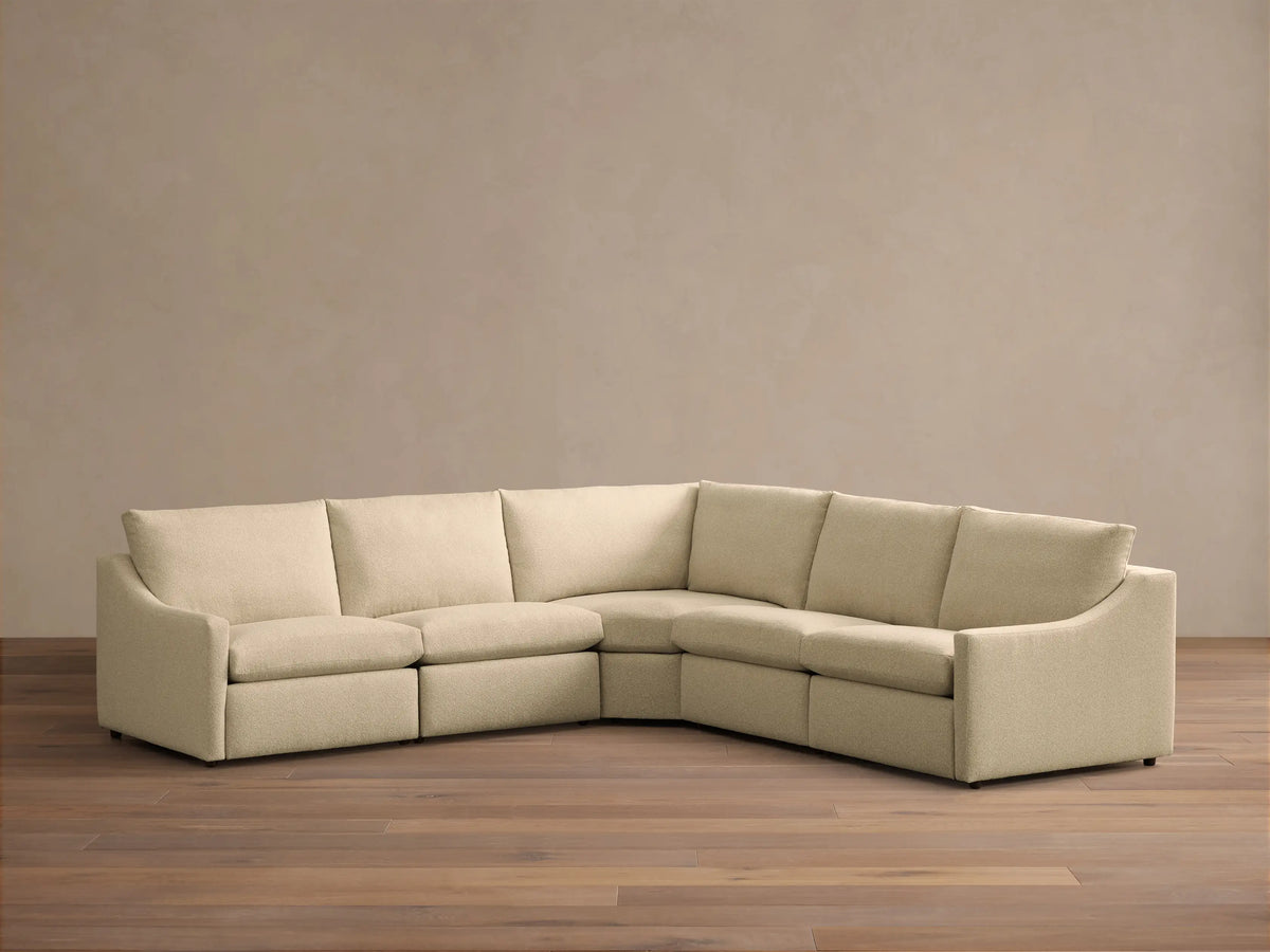 Front view of the cream Kipton Slope Arm Five-Piece Motion Corner Sectional™ with one seat reclined, extending a footrest.