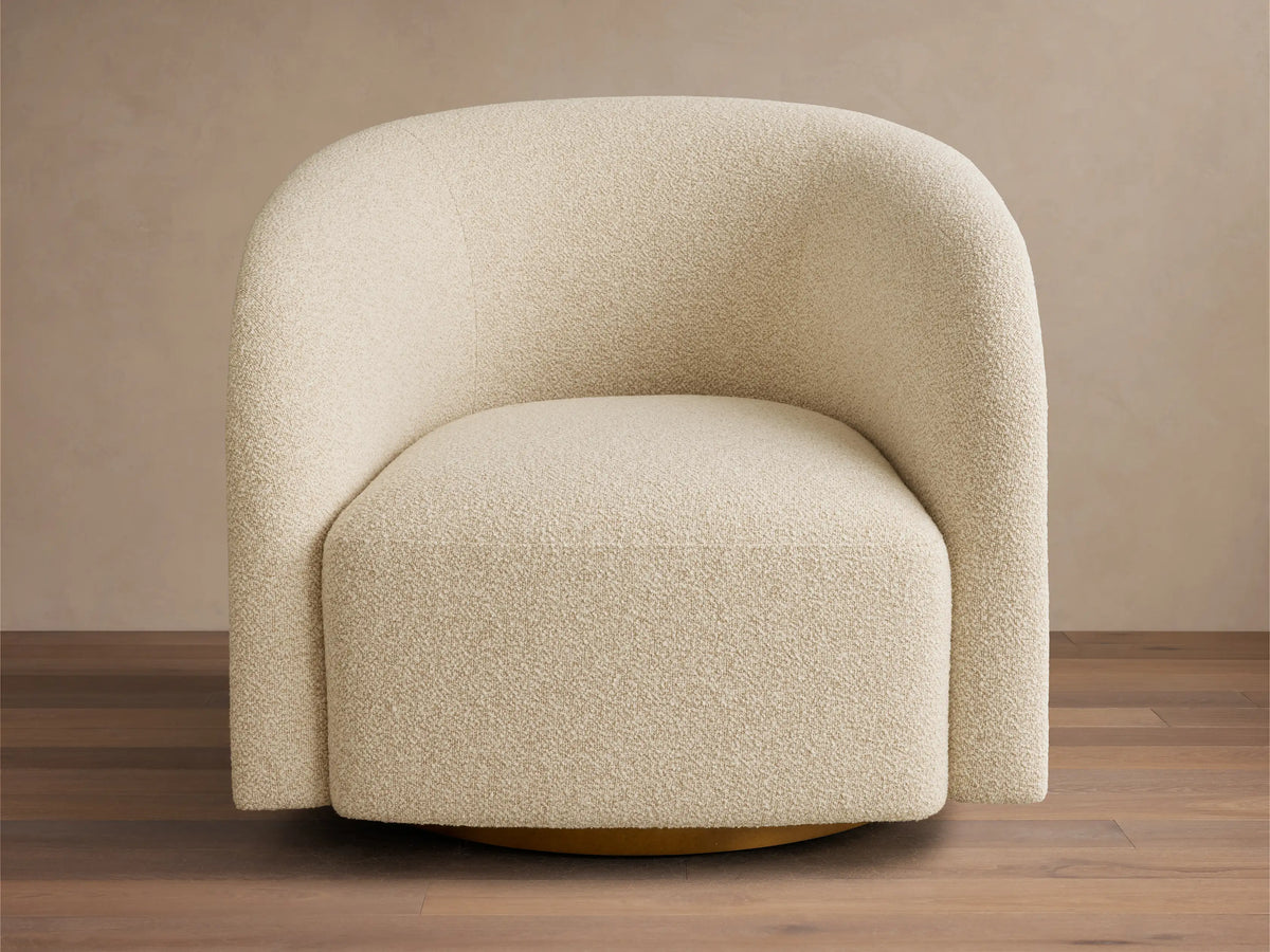 Front view of the cream Finnley Swivel Chair, featuring a rounded back, textured boucle-style fabric, and a golden base.